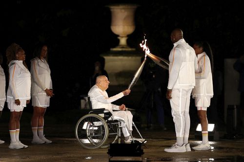Charles Coste, în scaun cu rotile, aprinzând torța lui Teddy Riner și Marie-Jose Perec, la ceremonia de deschidere a Jocurilor Olimpice de la Paris din 2024/Foto: Getty Images