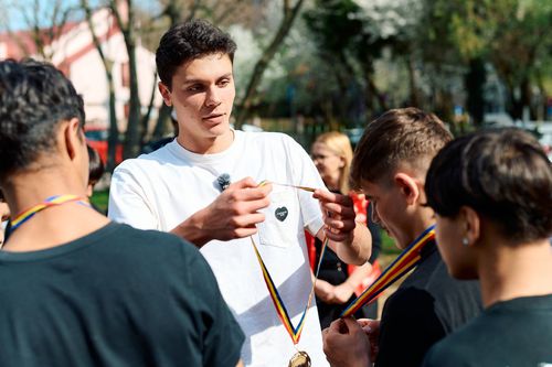 David Popovici în mijlocul adolescenților, oferindu-le medalii