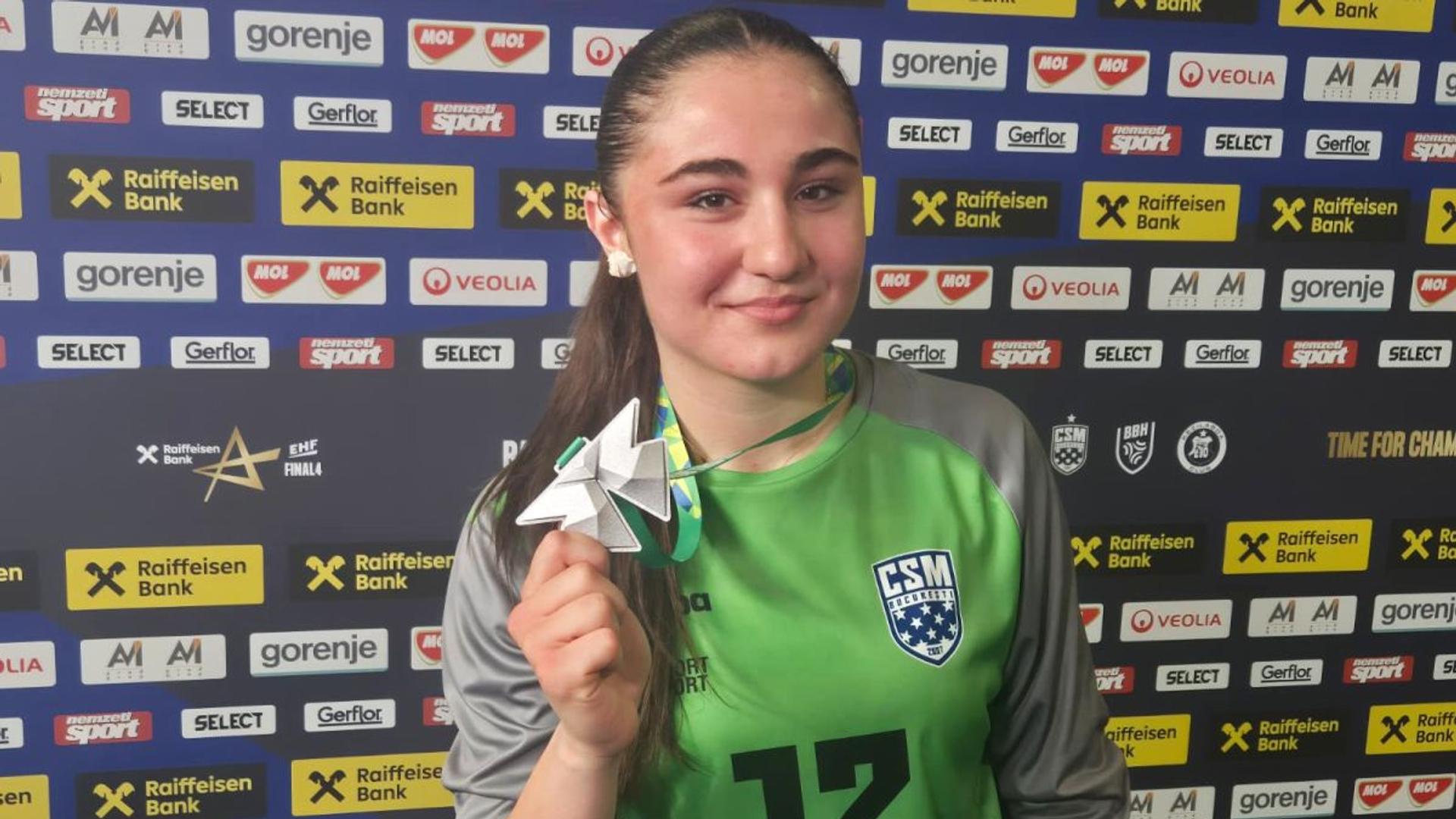 Alexia Chiru, portarul de 16 ani al echipei CSM București, în acțiune în timpul unui meci de handbal feminin intens și disputat. | sursa foto: Gazeta Sporturilor