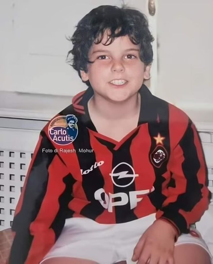 Carlo Acutis, surprins zâmbind către cameră, purtând echipamentul de acasă al echipei AC Milan din anii 1990.