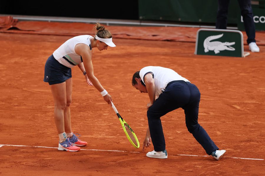 Krejcikova și arbitrul, examinând urma lăsată de minge pe zgură Noroc și Ghinion – frații gemeni ai tenisului