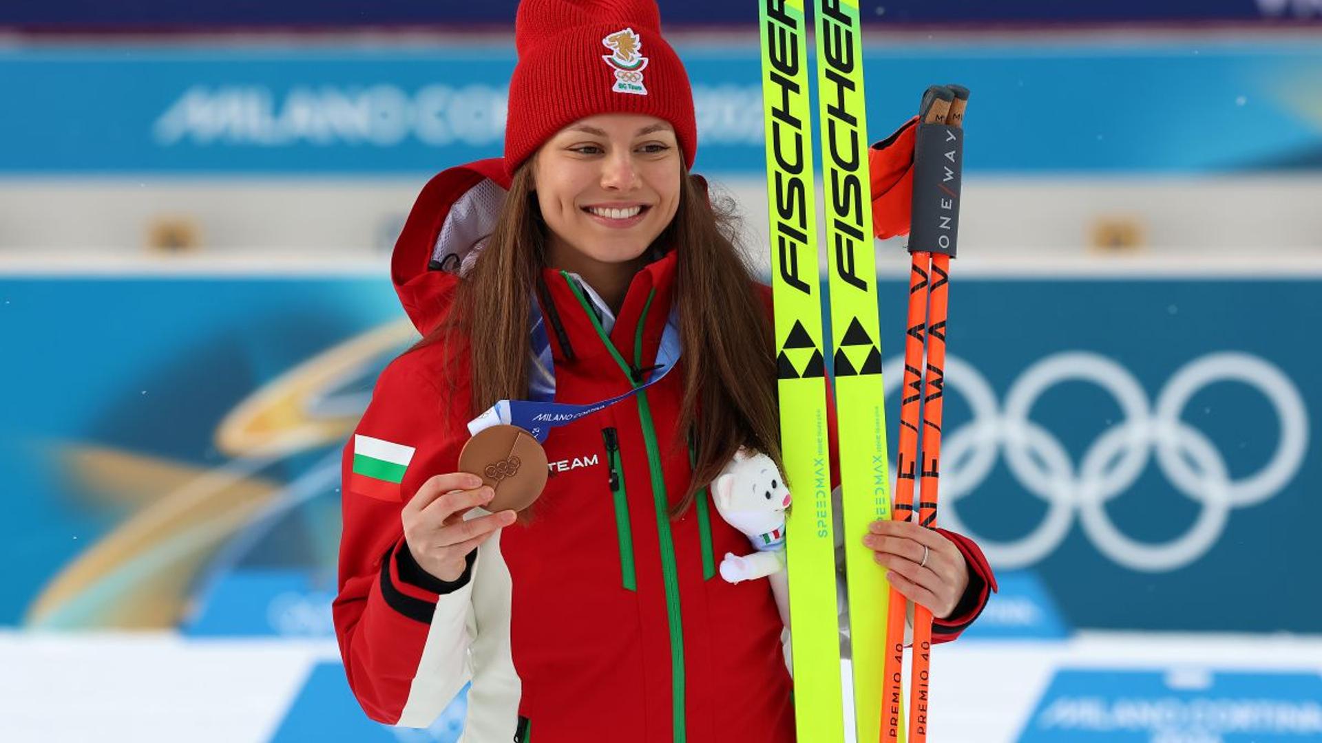 Lora Hristova pe podiumul olimpic primind medalia bronz la biatlon olimpic, însoțită de medaliatele cu aur și argint. | sursa foto: Gazeta Sporturilor Lora Hristova pe podiumul olimpic primind medalia bronz la biatlon olimpic, însoțită de medaliatele cu aur și argint. | sursa foto: Gazeta Sporturilor