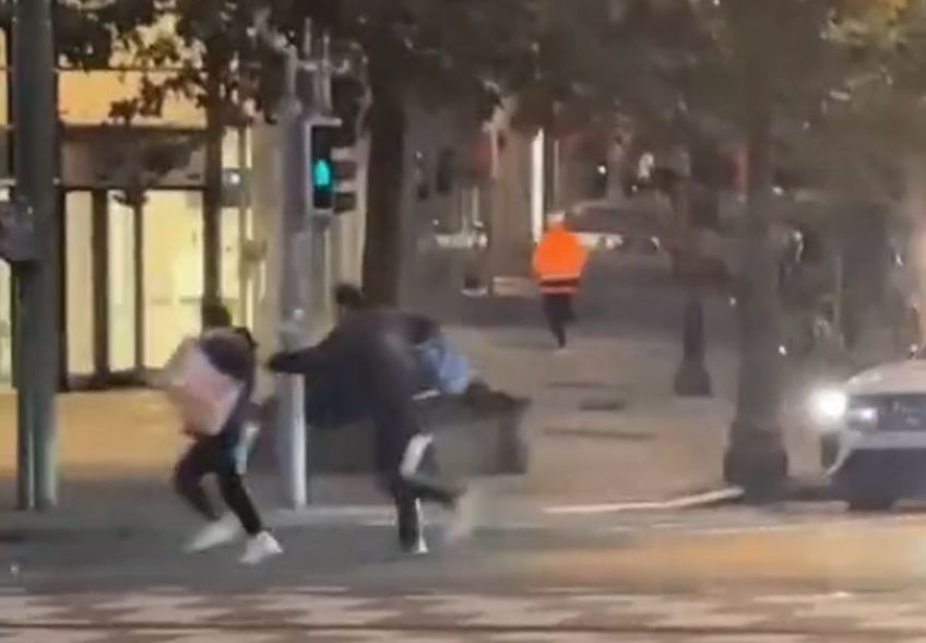 Atacatorul, în portocaliu, și doi trecători care fug de împușcături