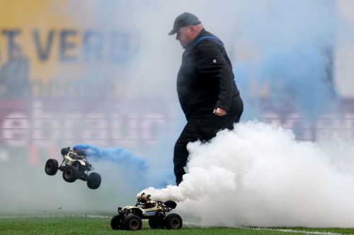 La Rostock, un om de ordine se chinuie să îndepărteze două mașinuțe teleghidate dotate cu fumigene / FotoGettyImages