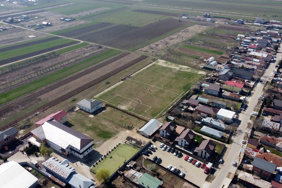 Imagine panoramică cu terenul din Cosoba, unde s-a jucat meciul cu Crevedia Mare „Jucăm printre tranșee, ca-n război!”. Reportaj GSP la Liga 5, cu fotbal, conducte de gaze și spectatori mascați: „Joacă titulari «Scoică», «Pisică», «Lună», «Buze moi»”