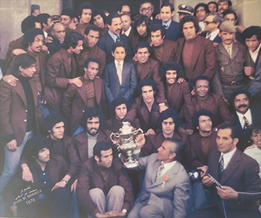 Selecționata Marocului, primită de Regele Hassan bin Muhammad (Hassan al 2-lea), după triumful la CAN 1976. Gil Mărdărescu este cel în costum gri, în partea de jos Românul care a cucerit Cupa Africii pe Națiuni » Povestea singurului antrenor din țara noastră care a câștigat un trofeu continental cu o echipă națională