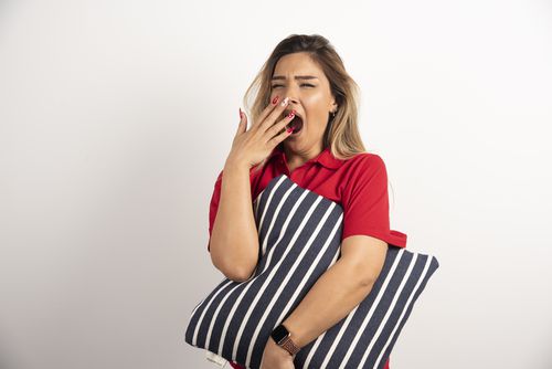 sleepy-young-woman-hugging-her-pillow-whiten-background