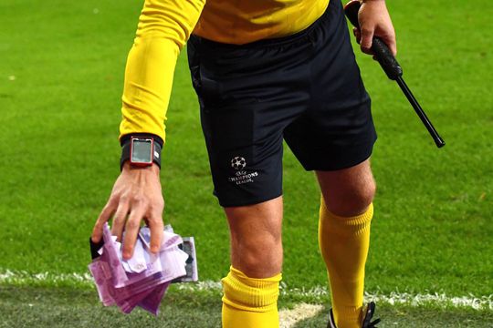 Un arbitru de rezervă strânge „banii de hârtie”  aruncați de fani la un meci de Liga Campionilor din 2017 // Foto: Imago