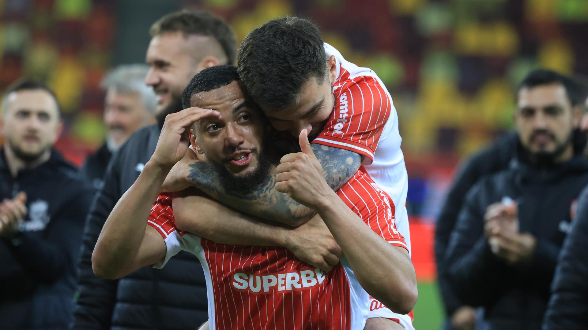 Jucători Dinamo sărbătorind victoria în derby-ul play-off fotbal, în timp ce Claudiu Petrila este asistat după accidentare gravă pe teren. | sursa foto: Gazeta Sporturilor