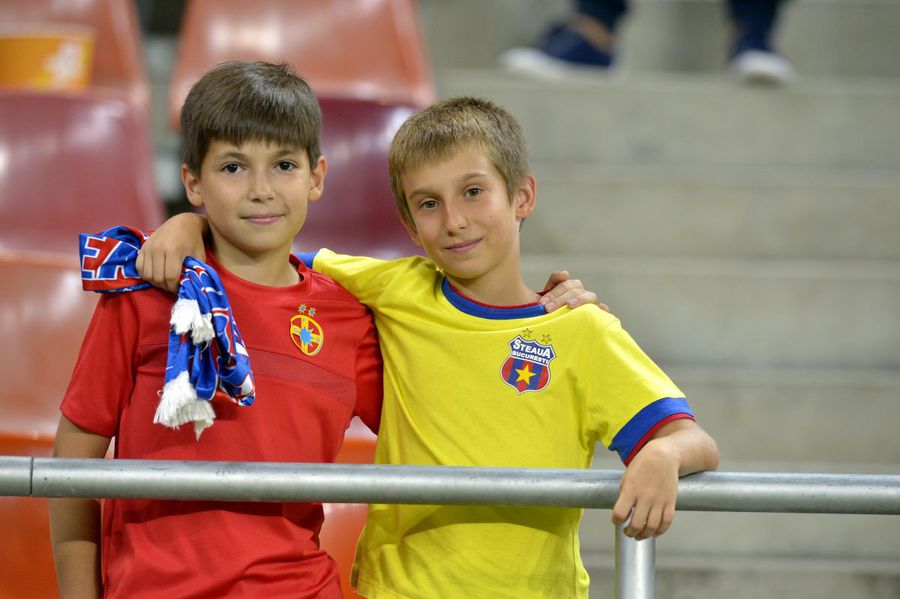 Doi tineri susținători ai actualei FCSB într-o fotografie care face cât 1.000 de cuvinte: unul are un tricou mai vechi, de când clubul se numea și avea sigla Steaua, celălalt echipat cu noua emblemă Războiul clonelor: Steaua, Dinamo, Rapid, U Craiova » Tabloul dureros al decăderii celor 4 imense branduri ale fotbalului românesc