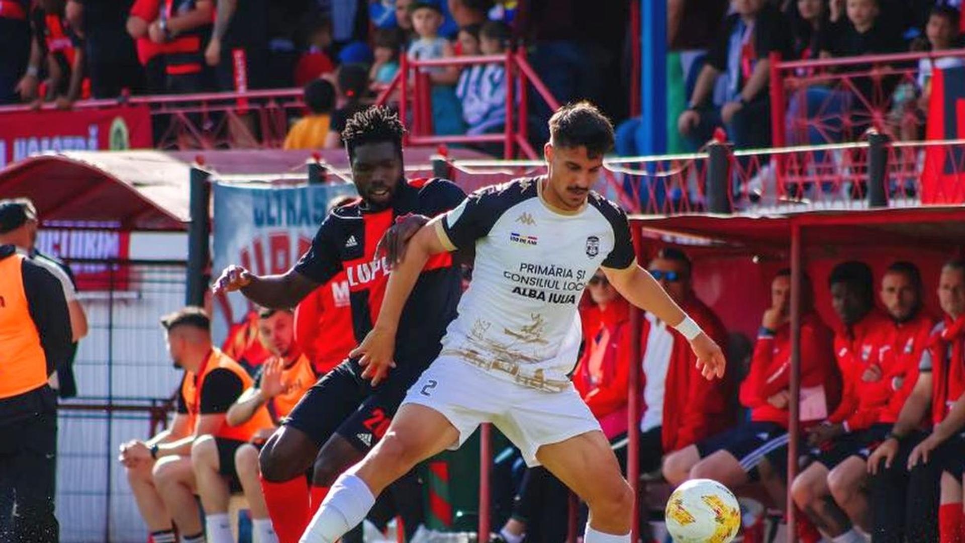 Jucători SC Popești Leordeni și CSM Unirea Alba Iulia în acțiune pe stadionul Inter Gaz la baraj promovare Liga 2, Liga 3 rezultate afișate pe ecran. | sursa foto: Gazeta Sporturilor